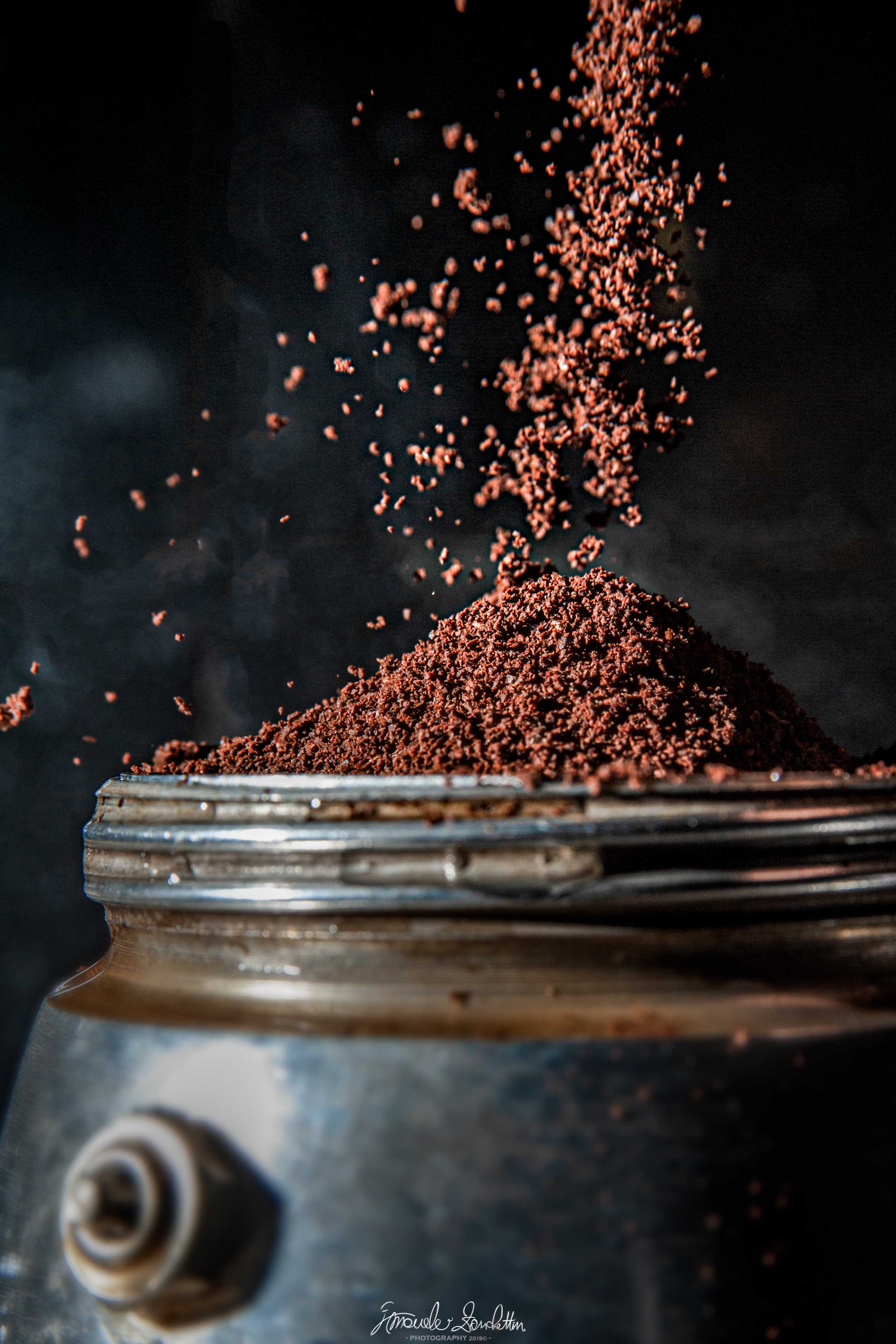 Granelli di caffè sospesi nell’aria sopra un barattolo di vetro aperto contro uno sfondo scuro