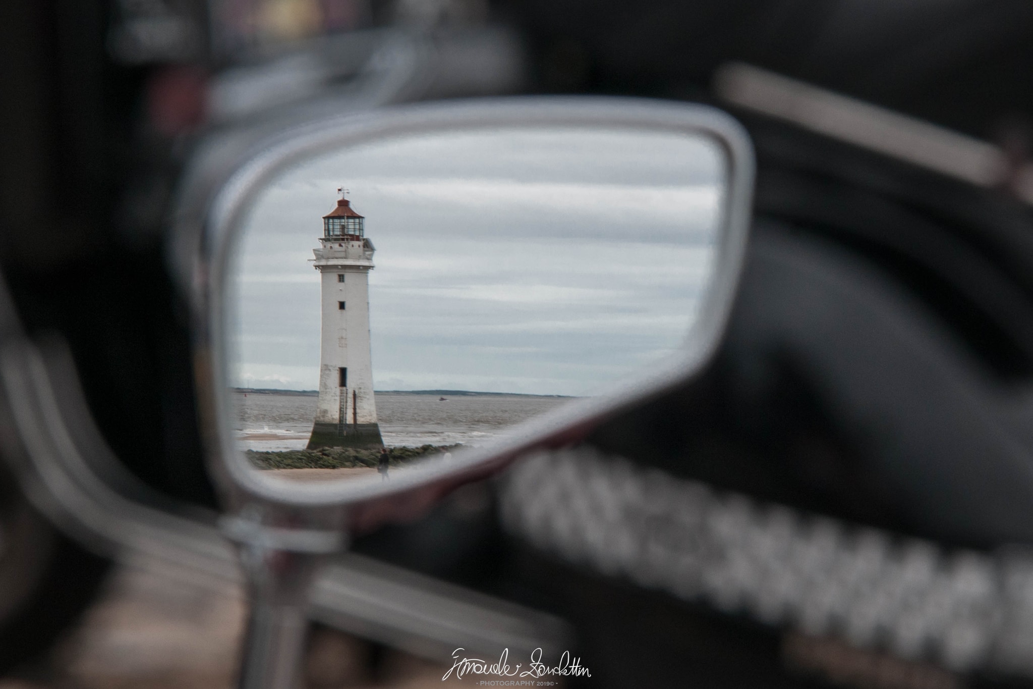 A lighthouse framed in a car wing mirror, photographed by Emanuele Zanchettin